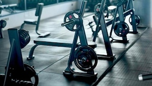 A gym with weightlifting equipment, large windows, and a patterned curtain. - 2-bedroom apartment in lovely Fumba Town with AC, modern comforts and balconies (Nyamanzi)
