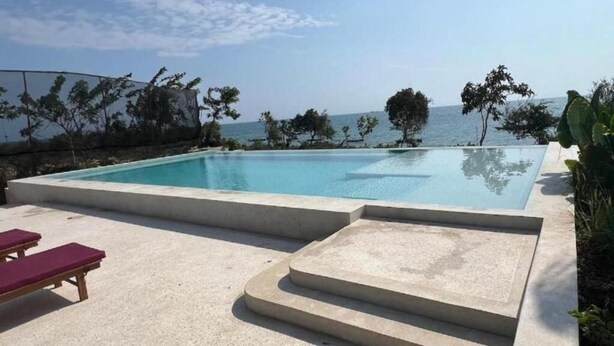 A rectangular swimming pool with steps leading into it, surrounded by a concrete deck with lounge chairs. - 2-bedroom apartment in lovely Fumba Town with AC, modern comforts and balconies (Nyamanzi)