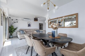 Ein modernes Wohnzimmer mit einem runden Esstisch, einem beigen Sofa und einem großen Spiegel.