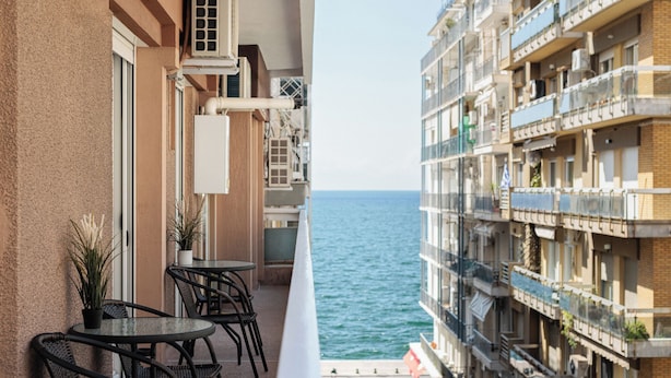 A balcony with outdoor furniture, air conditioning units, and a view of the sea. - Lumiere 3BD with Sea View City Center (Thessaloniki)