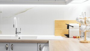 A modern kitchen with white cabinets, a stainless steel faucet, and a wooden countertop. - Lumiere 3BD with Sea View City Center (Thessaloniki)