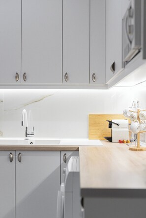 Una cucina moderna con pensili bianchi, un rubinetto in acciaio inossidabile e un piano di lavoro in legno.