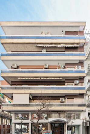 A multi-story building with balconies, air conditioning units, and a storefront at the ground level. - Lumiere 3BD with Sea View City Center (Thessaloniki)