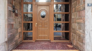 A wooden double door with a circular window, flanked by glass panels, and a number '8' sign on the wall. - Lumiere 3BD with Sea View City Center (Thessaloniki)