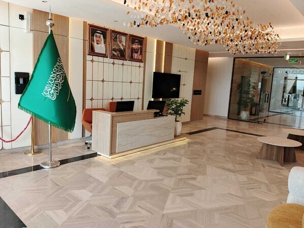 A reception area with a modern design, a reception desk, a television, and a decorative ceiling.