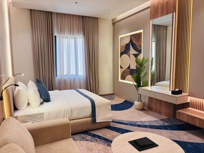 A hotel room with a bed, a bedside table, a mirror, a plant, and a round table.