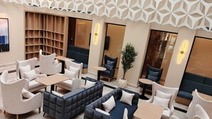 A modern lounge area with sofas, armchairs, and tables arranged for socializing. - Voyage Expo Suites (Riyadh)