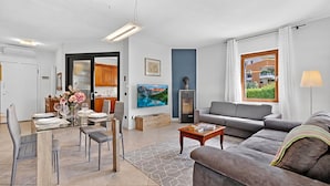 A modern living room with a sofa, dining table, and kitchen area visible through an open door. - Toniol Apartment (Riva del Garda)