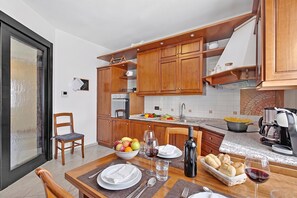 Eine moderne Küche mit Holzausstattung, einem Esstisch für zwei Personen und einer Kaffeemaschine.