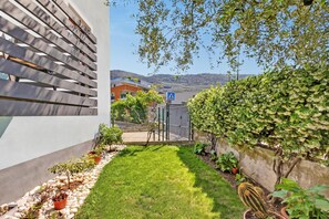 Ein modernes Gebäude mit geneigtem Dach, einem gepflasterten Weg und einem kleinen Garten mit verschiedenen Pflanzen.