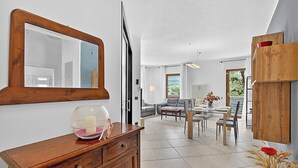 A modern living room with a dining area, a wooden cabinet, and a large mirror. - Toniol Apartment (Riva del Garda)