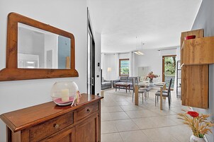 A modern living room with a dining area, a wooden cabinet, and a large mirror.