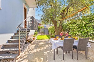 A patio with a table set for dining, a staircase, and a garden area.