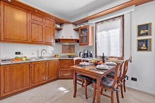A kitchen with wooden cabinets, a dining table with chairs, and a window with a curtain.