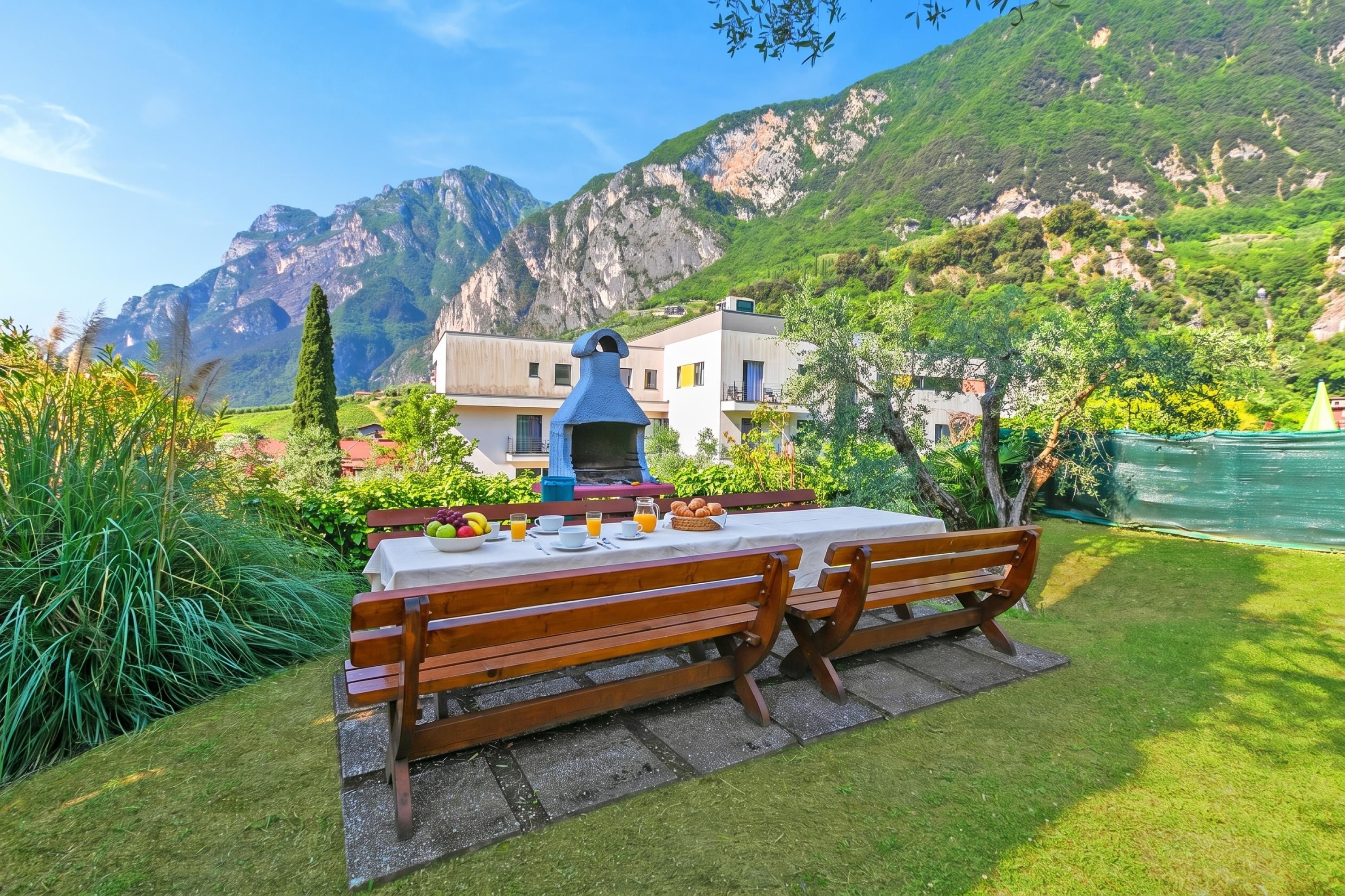Une table à manger avec des bancs, une cheminée bleue et une vue sur les montagnes en arrière-plan.