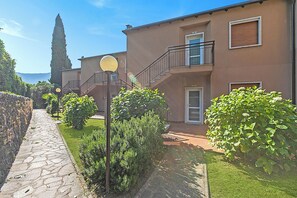 A residential building with a stone pathway, a staircase, and a view of the sea. - Lagotissimo 17 (Riva del Garda)
