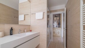 Un baño moderno con un lavamanos grande, un espejo y un perchero para toallas.