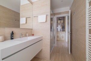 Un bagno moderno con un lavandino capiente, uno specchio e un portasciugamani.
