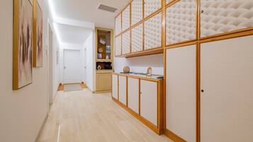 A hallway with a wooden cabinet, a door, and a shelf with items.