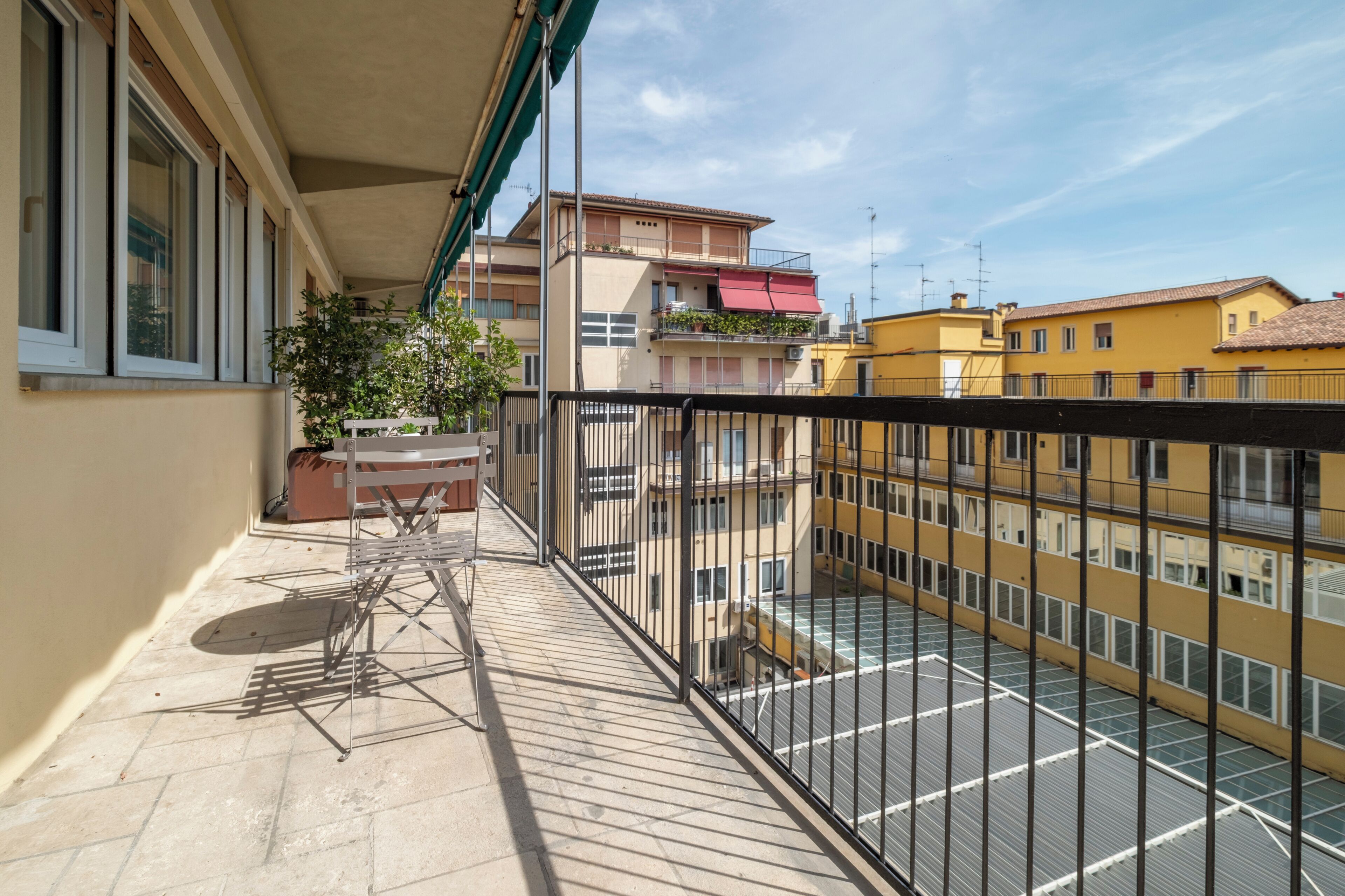 A balcony with a table, chairs, and a potted plant.