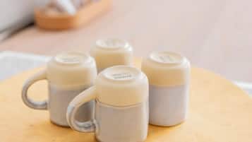 Une table ronde sur laquelle se trouvent quatre tasses en céramique, disposées sur un plateau.