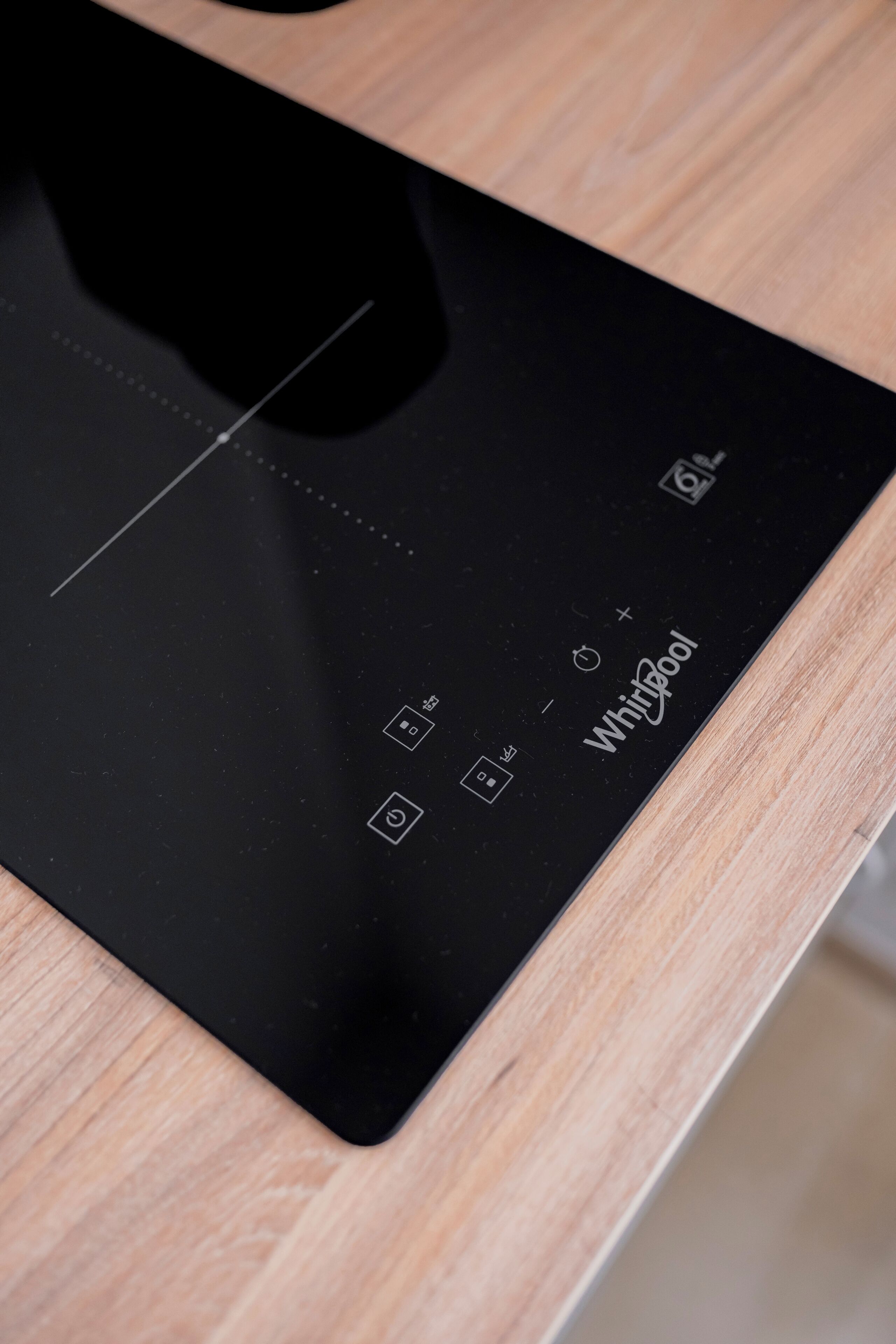 Een zwarte Whirlpool inductiekookplaat op een houten aanrecht.