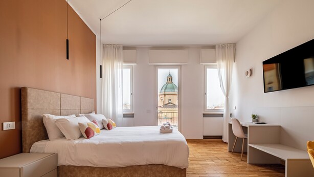Una habitación de hotel moderna con cama, mesitas de noche, escritorio y televisor.