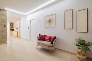 A modern interior with a beige sofa, a potted plant, and framed artwork on the wall. - Urbanicooh Cavour Rooms&Suite (Bologna)