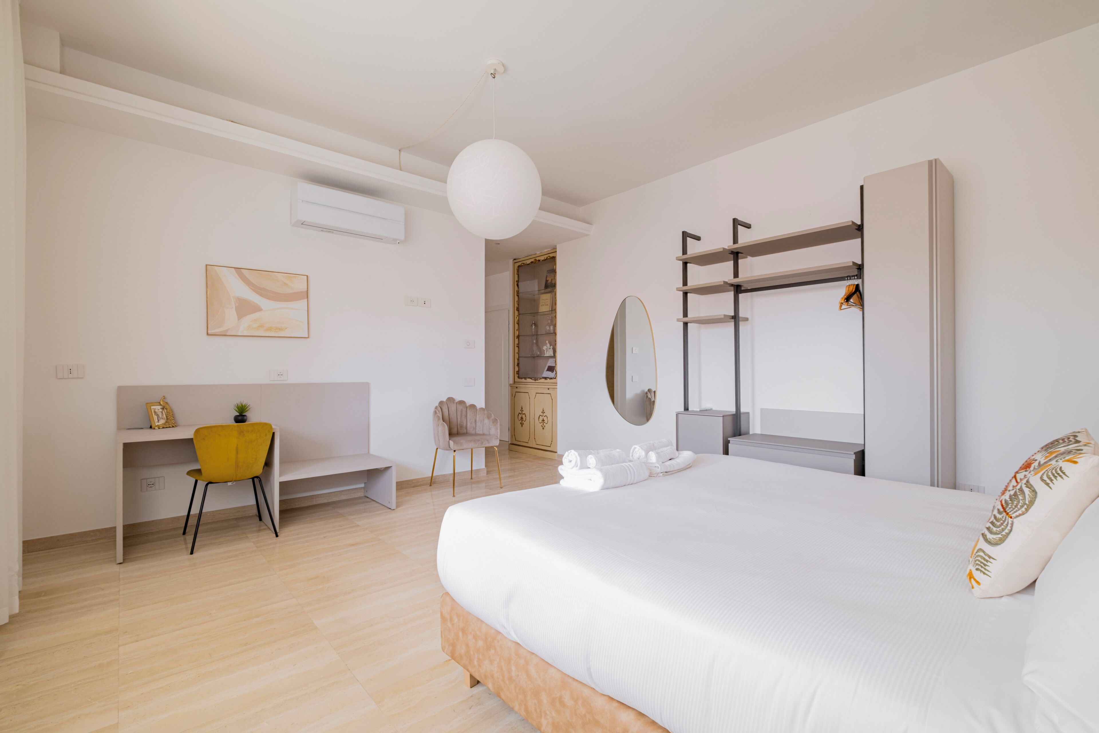 Una habitación de hotel moderna con cama, escritorio, silla, armario y espejo.