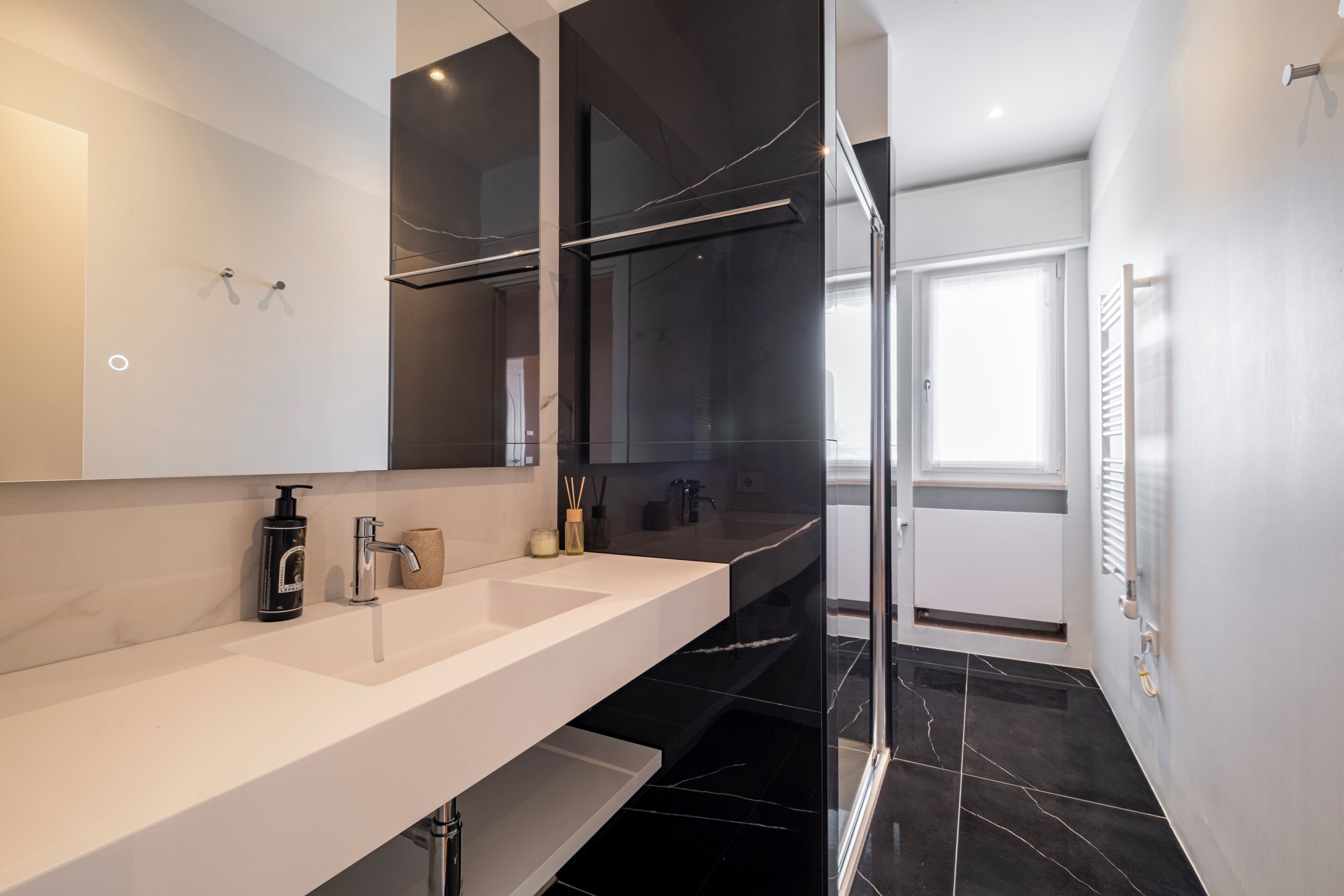 A modern bathroom with a white vanity, a glass shower enclosure, and a large mirror.
