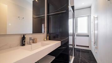 A modern bathroom with a white vanity, a glass shower enclosure, and a large mirror.