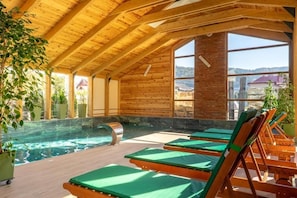 A wooden interior with a pool, lounge chairs, and large windows. - Forest Green & SPA (Gura Humorului)