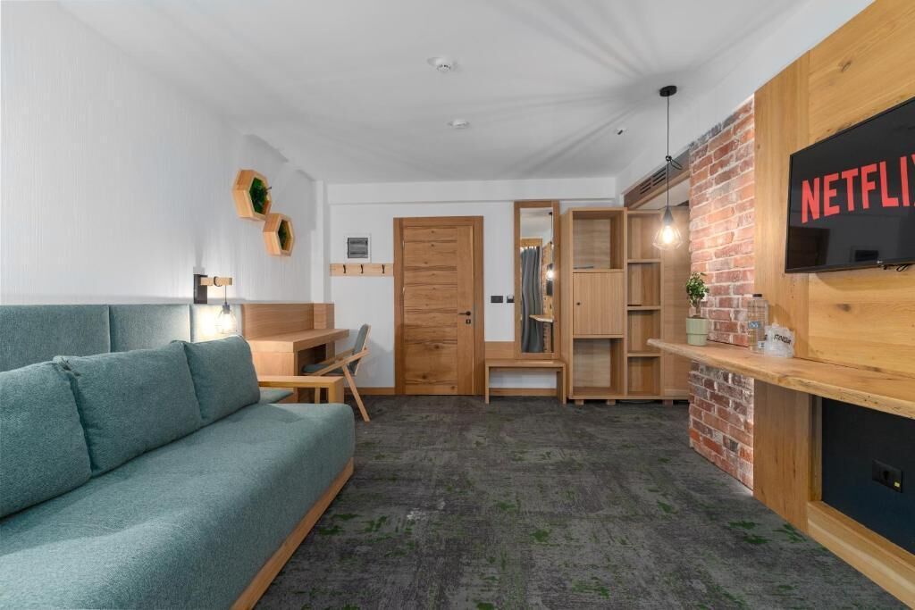 Una sala moderna con sofá, muebles de madera, pared decorativa de ladrillo y el logo de Netflix.