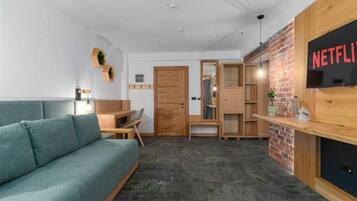 A modern living room with a sofa, wooden furniture, a brick accent wall, and a Netflix sign.
