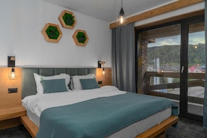 A bedroom with a bed, two bedside tables, a window with a view, and three hexagonal wall decorations. - Forest Green & SPA (Gura Humorului)