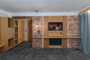 A room with a brick wall, wooden shelves, a mounted TV, and a door.