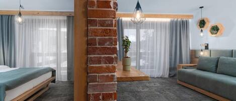 Una habitación moderna con una pared de ladrillo decorativa, una cama, un sofá y una lámpara colgante.