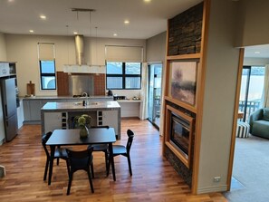 Eine moderne Küche mit einer Kochinsel, einem Essbereich mit Tisch und Stühlen sowie einem Kamin.