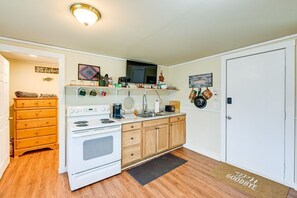 A compact kitchen with a stove, microwave, and wooden cabinets. - BabyBears Peaceful cabin & hot tub (Whittier)
