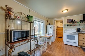 A compact kitchen with a microwave, stove, refrigerator, and a dining area with a chair and table. - BabyBears Peaceful cabin & hot tub (Whittier)
