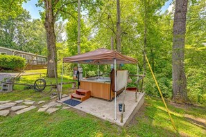 A hot tub setup with a wooden deck, steps, and a canopy in a wooded area. - BabyBears Peaceful cabin & hot tub (Whittier)