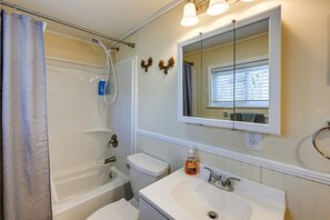 A bathroom with a bathtub, toilet, sink, and a mirror. - BabyBears Peaceful cabin & hot tub (Whittier)