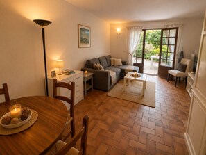 Ein gemütliches Wohnzimmer mit einer Couch, einem Esstisch mit Stühlen, einer Lampe und einem Fenster mit Vorhängen.