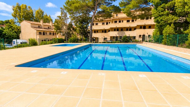 Piscina com água azul cristalina, rodeada por um deck revestido de azulejos.