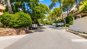 Eine Wohnstraße mit parkenden Autos, Steinmauern und Bäumen.