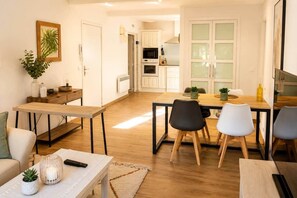 Ein modernes Wohnzimmer mit Essbereich, Holzboden und einer Küche im Hintergrund.