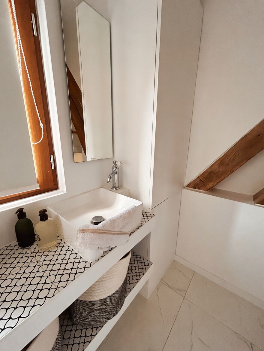 A bathroom with a white sink, mirror, and tiled floor.