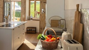 A kitchen with a wooden ceiling, a white countertop, a toaster, and a basket of fruit. - La Maison de la Tour (Léré)