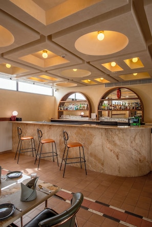 A bar area with a marble counter, bar stools, and a well-stocked shelf with bottles and glasses. - Tree of Life Ganga Dwar Haridwar (Haridwar)
