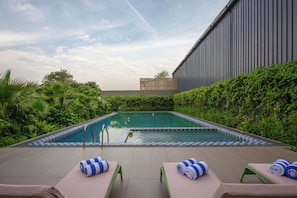 Una piscina con sillas de descanso y un edificio grande al fondo.